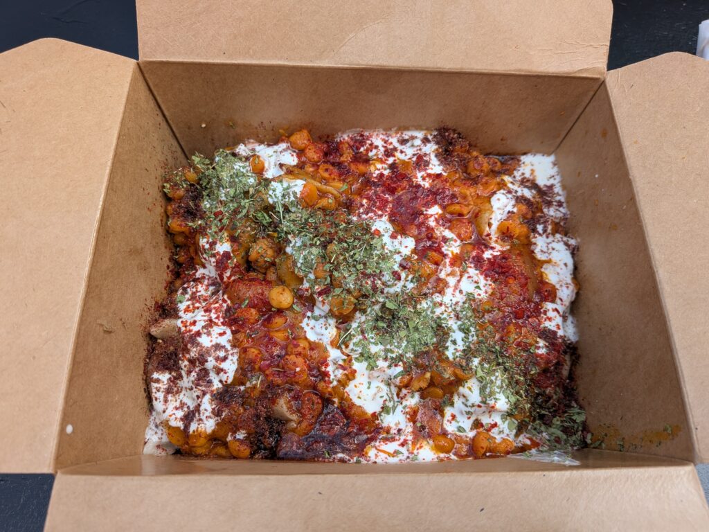 A cardboard box with orange chickpeas, mint, yoghurt and sumac all over